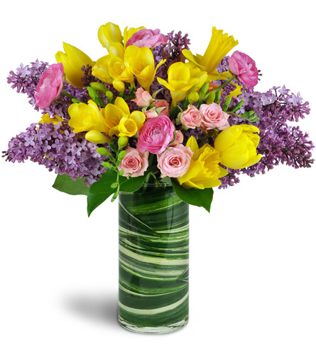 Spring Smiles™. An arrangement by Avenue Flowers and Gifts. Lilacs, tulips, and more are gorgeously arranged in a glass vase..