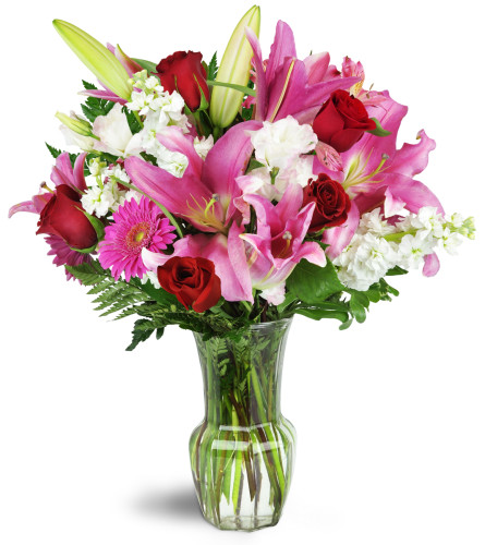 Blushing Heart Bouquet™ - Deluxe. An arrangement by Avenue Flowers and Gifts. Deep red roses, lush lilies, and pretty pink Gerbera daisies are...